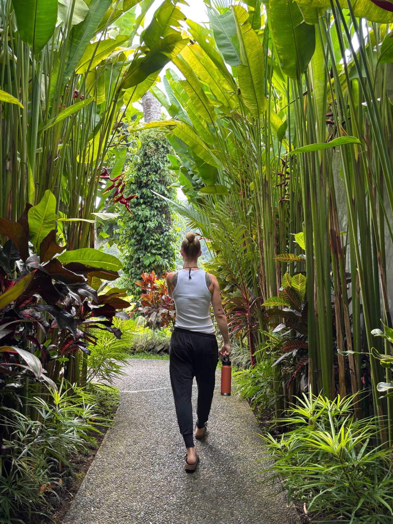 Kaylea walking along a stone path through a lush tropical garden